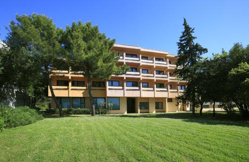 un immeuble d'appartements avec une pelouse devant lui dans l'établissement Hotel Donat - All Inclusive, à Zadar