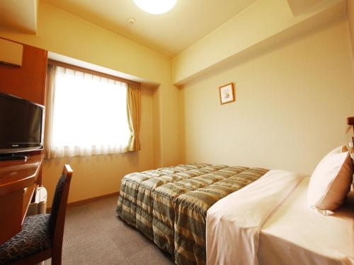 a hotel room with a bed and a television at Hotel Route-Inn Honjo Ekiminami in Honjo
