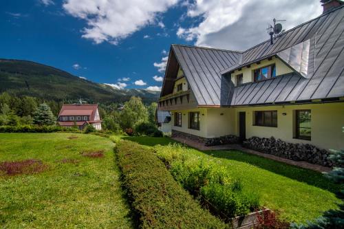 ein Haus mit einem Rasenplatz neben einem Haus in der Unterkunft Pension Aspen in Špindlerův Mlýn