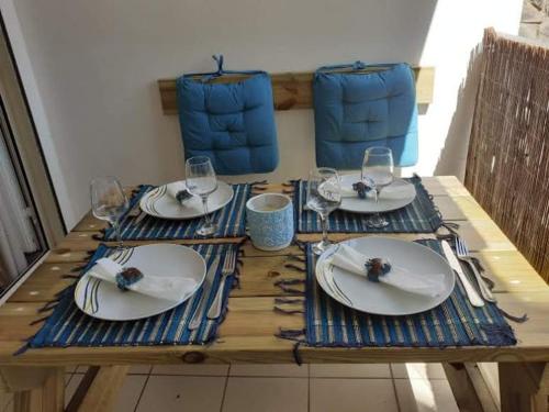 una mesa de madera con platos y copas de vino. en Appart Sophyann, en Saint-Gilles-les-Bains