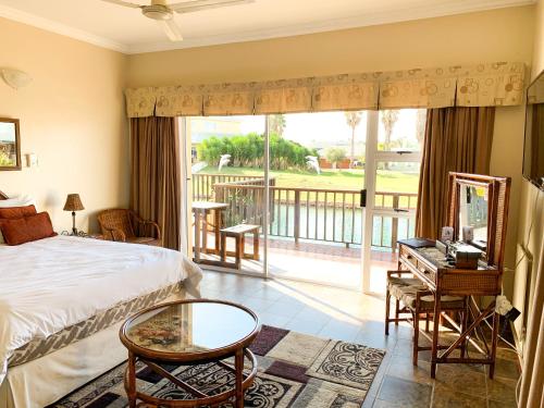 a bedroom with a bed and a balcony at Marina Martinique B&B in Jeffreys Bay