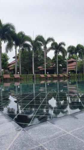a pool of water with palm trees in the background at Pruksa Resort Prachuabkhirikhan in Prachuap Khiri Khan