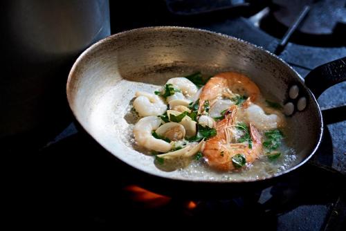 a pan filled with shrimp and mushrooms on a stove at Valentino s Restaurant with Rooms in Ripon