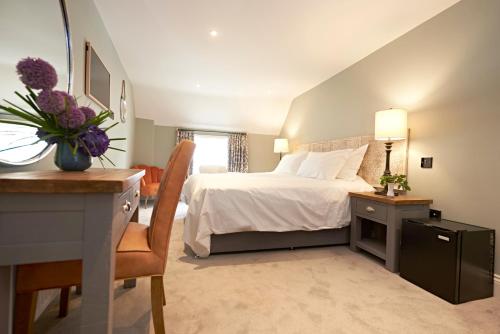 a bedroom with a white bed and a desk and a chair at Valentino s Restaurant with Rooms in Ripon