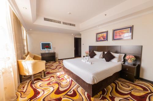 een hotelkamer met een bed en een stoel bij Ewan Ajman Suites Hotel in Ajman 