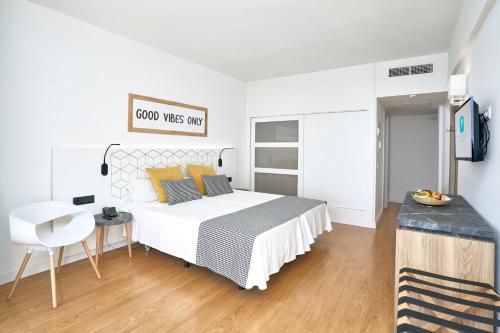 a white bedroom with a bed and a desk at Flamboyan Caribe Hotel & Spa in Magaluf