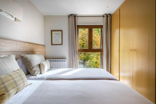 a bedroom with a white bed and a window at MONTELIA Ático El Ciervo de Panticosa in Panticosa
