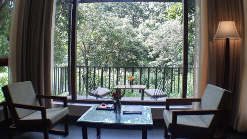a room with a table and chairs and a large window at Saraca Resort & Spa Corbett in Garjia