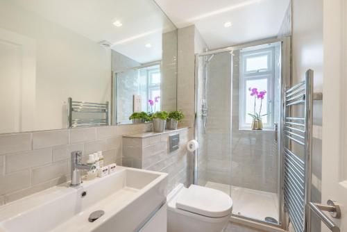La salle de bains est pourvue d'un lavabo, de toilettes et d'une douche. dans l'établissement Marylebone - Wyndham Street by Viridian Apartments, à Londres