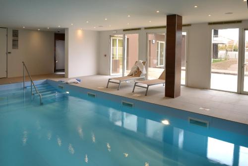 a swimming pool with two chairs in a building at Domitys Les Tours d'Or in Perpignan