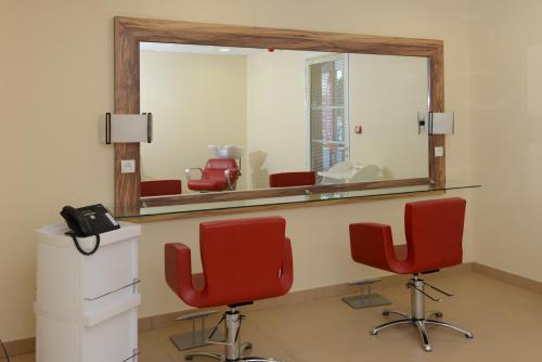 - une salle d'attente avec 2 chaises rouges et un miroir dans l'établissement Domitys Les Tours d'Or, à Perpignan