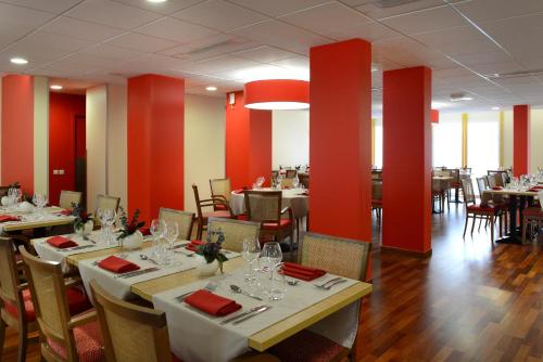 une salle à manger avec des tables, des chaises et des murs rouges dans l'établissement Domitys Les Tours d'Or, à Perpignan