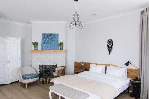 een witte slaapkamer met een bed en een stoel bij Bobritsa Dacha in Bobritsa