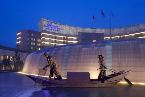 a statue of two men in a boat in front of a building at Fairmont Yangcheng Lake in Kunshan