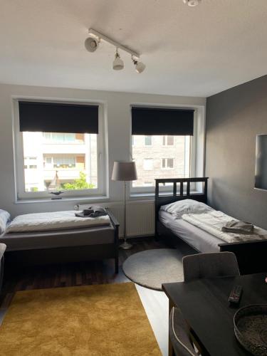 a room with two beds and a table and two windows at City Studio Apartment in Bremerhaven