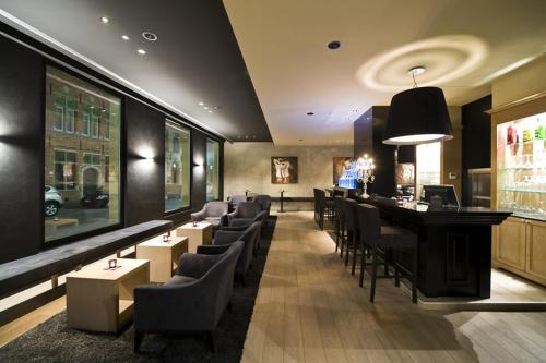 a restaurant with a bar with tables and chairs at Flanders Hotel in Bruges