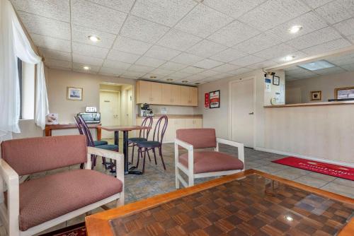 a room with chairs and a table and a kitchen at Econo Lodge Dewitt I-90 in DeWitt