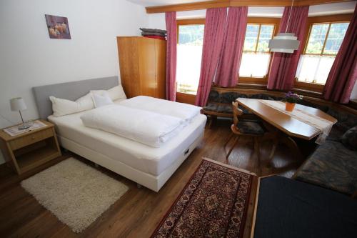 een slaapkamer met een wit bed, een tafel en ramen bij Eva Dabernig in Zell am Ziller
