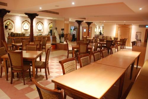 ein Restaurant mit Tischen und Stühlen und Menschen im Hintergrund in der Unterkunft PLA Krishna Inn in Tiruchchirāppalli