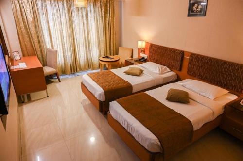a hotel room with two beds and a television at PLA Krishna Inn in Tiruchirappalli