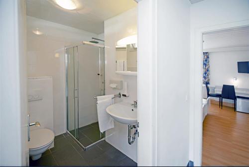 ein Bad mit einem Waschbecken, einem WC und einer Dusche in der Unterkunft Murgtal Motel in Rastatt