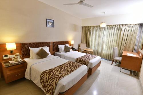 Una habitación de hotel con dos camas y un escritorio. en PLA Krishna Inn, en Tiruchchirāppalli