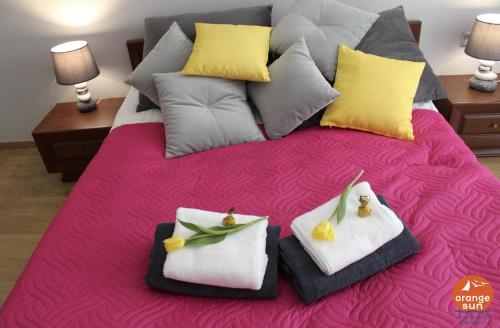 ein Bett mit Handtüchern und Blumen darüber in der Unterkunft Apartament Orange Sun nr°6 in Pobierowo