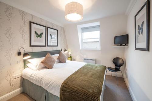 a bedroom with a large bed and a television at Marylebone - Chiltern Street by Viridian Apartments in London