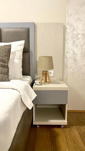 a bed with a nightstand with a lamp on it at Hotel Olimpija plus in Herceg-Novi