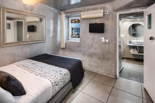 a bedroom with a bed and a bathroom with a sink at Katerina's Castle - Caldera Cave Hotel in Imerovigli