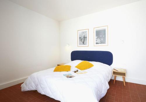 1 dormitorio con 1 cama blanca grande con almohadas amarillas en Résidence Néméa Les Carrats - Port Leucate, en Port Leucate