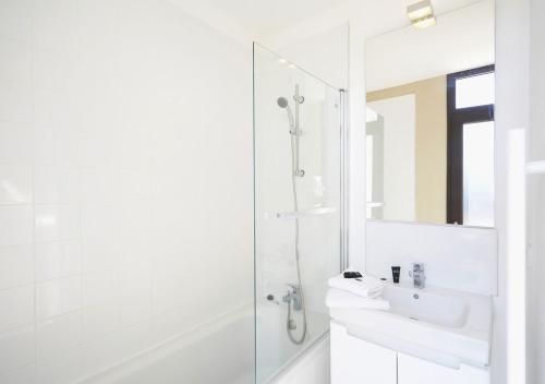 uma casa de banho branca com um lavatório e um chuveiro em Résidence Néméa Les Carrats - Port Leucate em Port Leucate