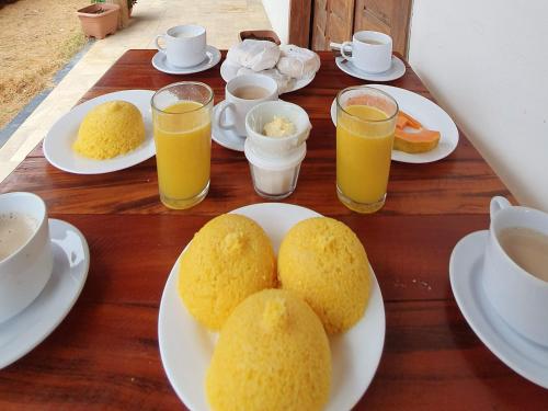 a table with plates of food and cups of orange juice at Pousada Vila Cajuína - Parnaíba in Parnaíba