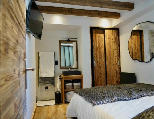 een slaapkamer met een bed en een televisie en een spiegel bij SUPERBE DUPLEX 4* DERNIER ETAGE 7pers. / 67m2 in Huez