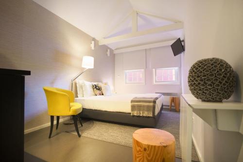 una camera da letto con un letto e una sedia gialla di Stay in Apartments Ribeira 24 a Porto