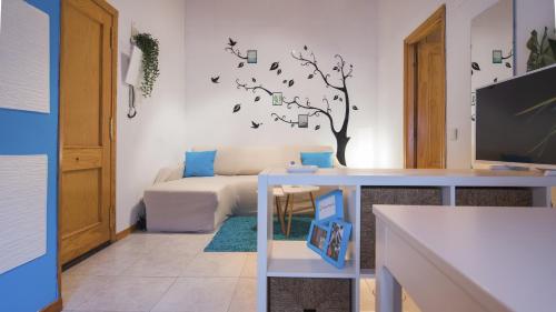 uma sala de estar com um sofá e uma árvore na parede em La Casita del Árbol em Toledo