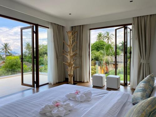 een slaapkamer met een groot wit bed en 2 witte handdoeken bij Villa Tango Victoria Resort, Koh Yao Noi in Ko Yao Noi