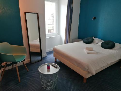 ein Schlafzimmer mit einem Bett, einem Spiegel und einem Stuhl in der Unterkunft ARÔMA - anciennement l'Instant B in Blain