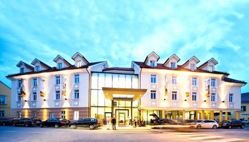 um grande edifício branco com carros estacionados em frente em Hotel Stainzerhof em Stainz