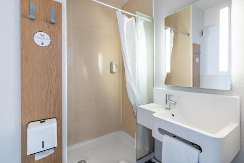 een witte badkamer met een wastafel en een douche bij B&B HOTEL Bordeaux Sud Mios in Mios