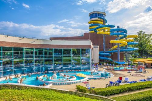 a large pool with a water slide in front of a building at Hunguest Szeged - ex Forrás in Szeged