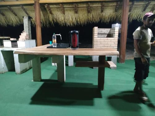 a man standing in front of a wooden table at Casa na Praia de Ponta de Pedras in Alter do Chao