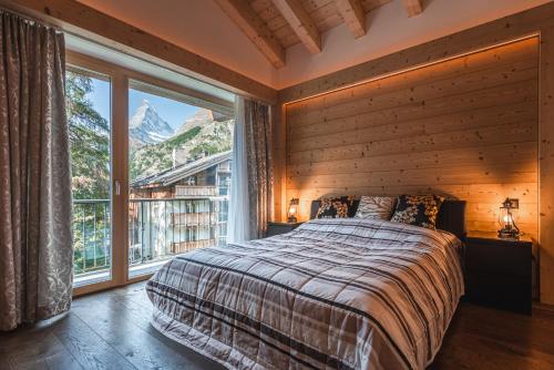 - une chambre avec un lit et une grande fenêtre dans l'établissement Joe's Place - luxury lifestyle apartment, à Zermatt