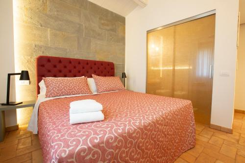a bedroom with a red bed with two towels on it at Agriturismo Torre del Marino in Brisighella