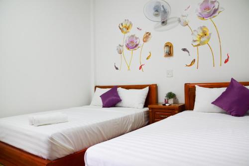 two beds in a room with flowers on the wall at Blossom Homestay in Tuy Hoa