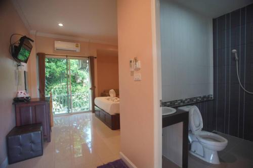 a bathroom with a toilet and a sink and a bed at Wangka Resort in Sangkhla Buri