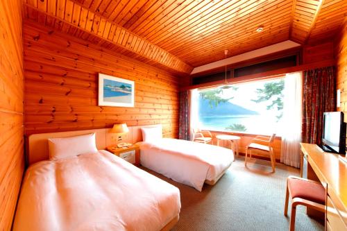 a bedroom with two beds and a desk and a television at Grand Park Hotel Okubiwako Makino in Takashima