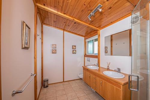 a bathroom with two sinks and a wooden ceiling at Mountainview Villa Luxury Lodge & Glamping in Blenheim