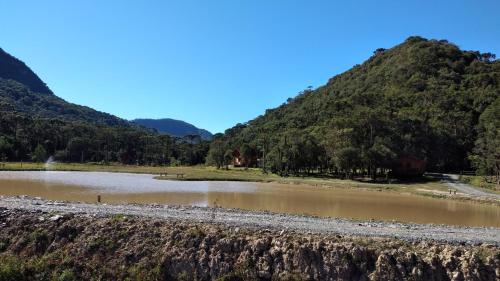 a river in a field with mountains in the background at Pousada Vale da Imbuia chalé para temporada in Urubici