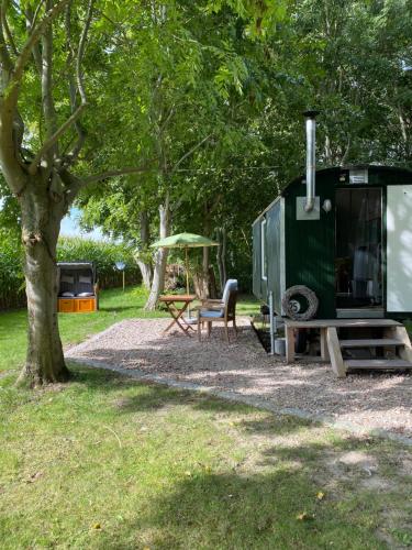 a trailer and a picnic table and a tree at Bauwagen - Gut Groß Fedderwarden in Butjadingen